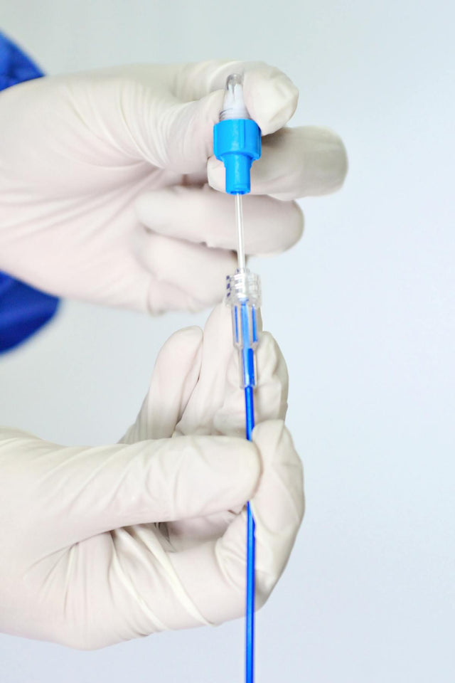 Gloved hands handling catheter